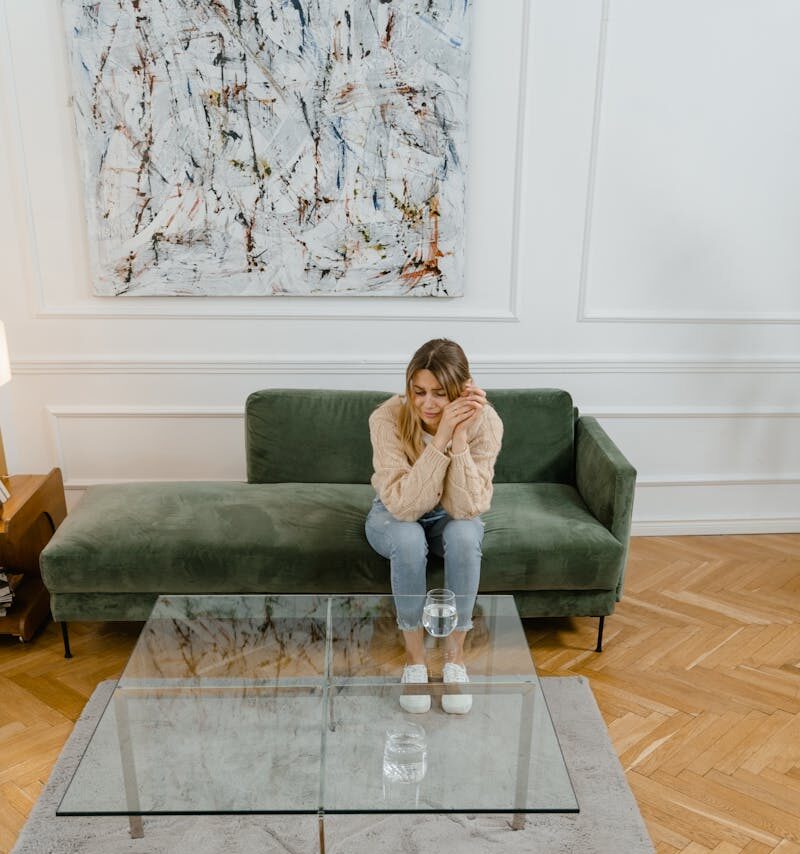 A woman in a therapy session indoors, reflecting emotions with a therapist.